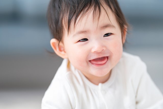 白い服を着て笑顔を見せる赤ちゃん